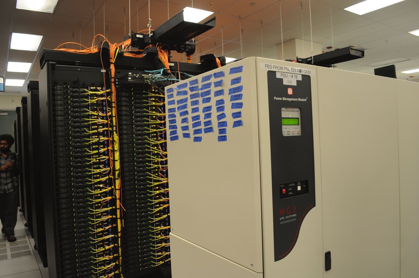UPS unit beside server racks with network cabling